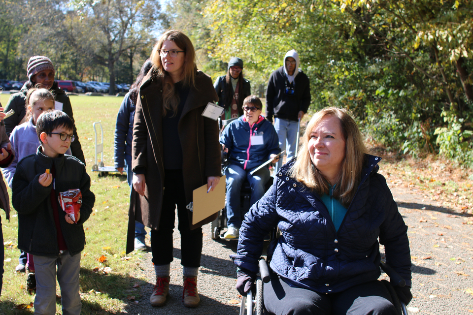 landscape of a volunteer leading several individuals in wheelchairs along a portion of the trail