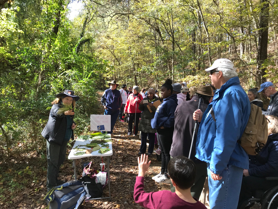 landscape of a volunteer taking questions from attendees along a trail