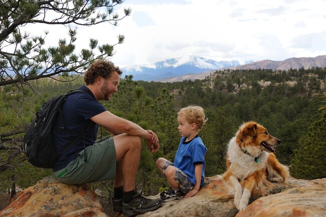 Taking a breather at Ute Valley Gateway outside of Colorado Springs Father, son, and dog rest on a hike
