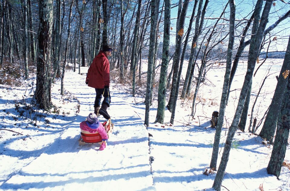 A man pulls a child in a sled in the Rachel Carson National Wildlife Refuge, Wells, ME.