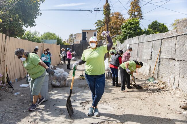 A woman wearing a dust mask stops to pose for the camera at a park clean-up